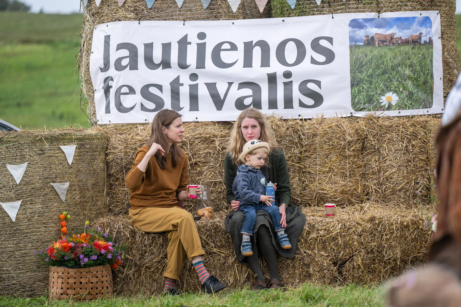 Šeima prie Jautienos festivalio baneris ant šiaudų ryšulių